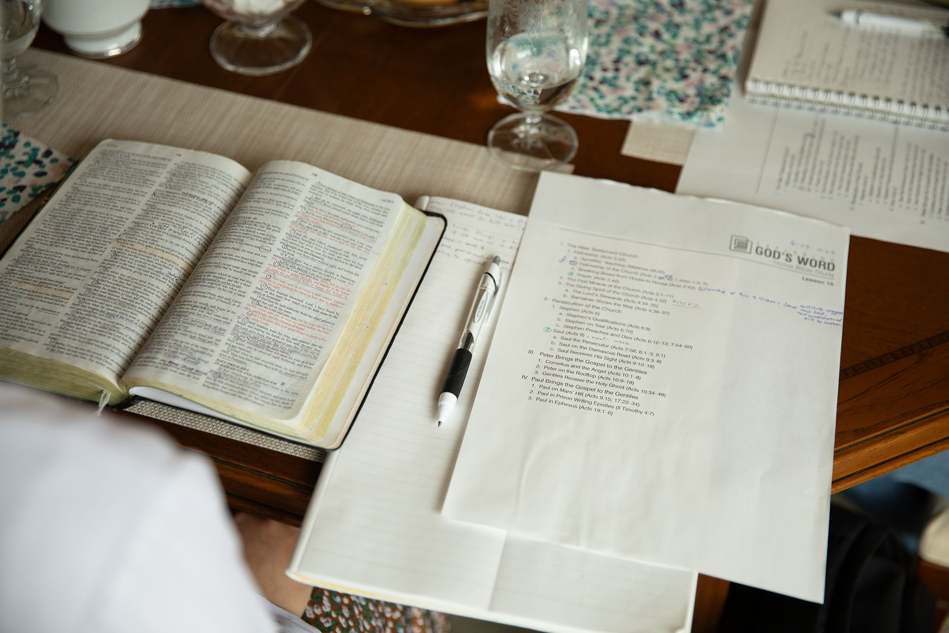 Bible laying open next to notes on a table